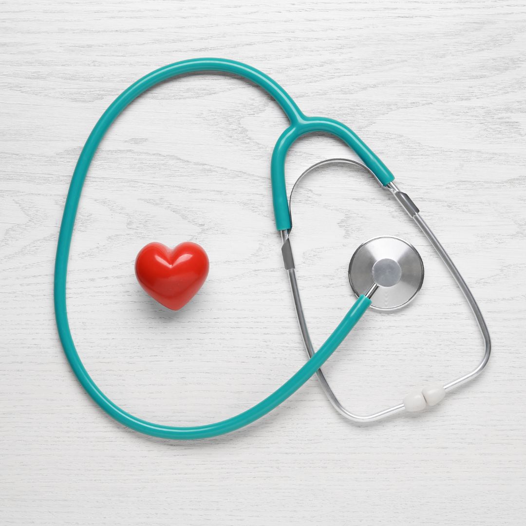 Blue stethescope surrounding a fake heart. 