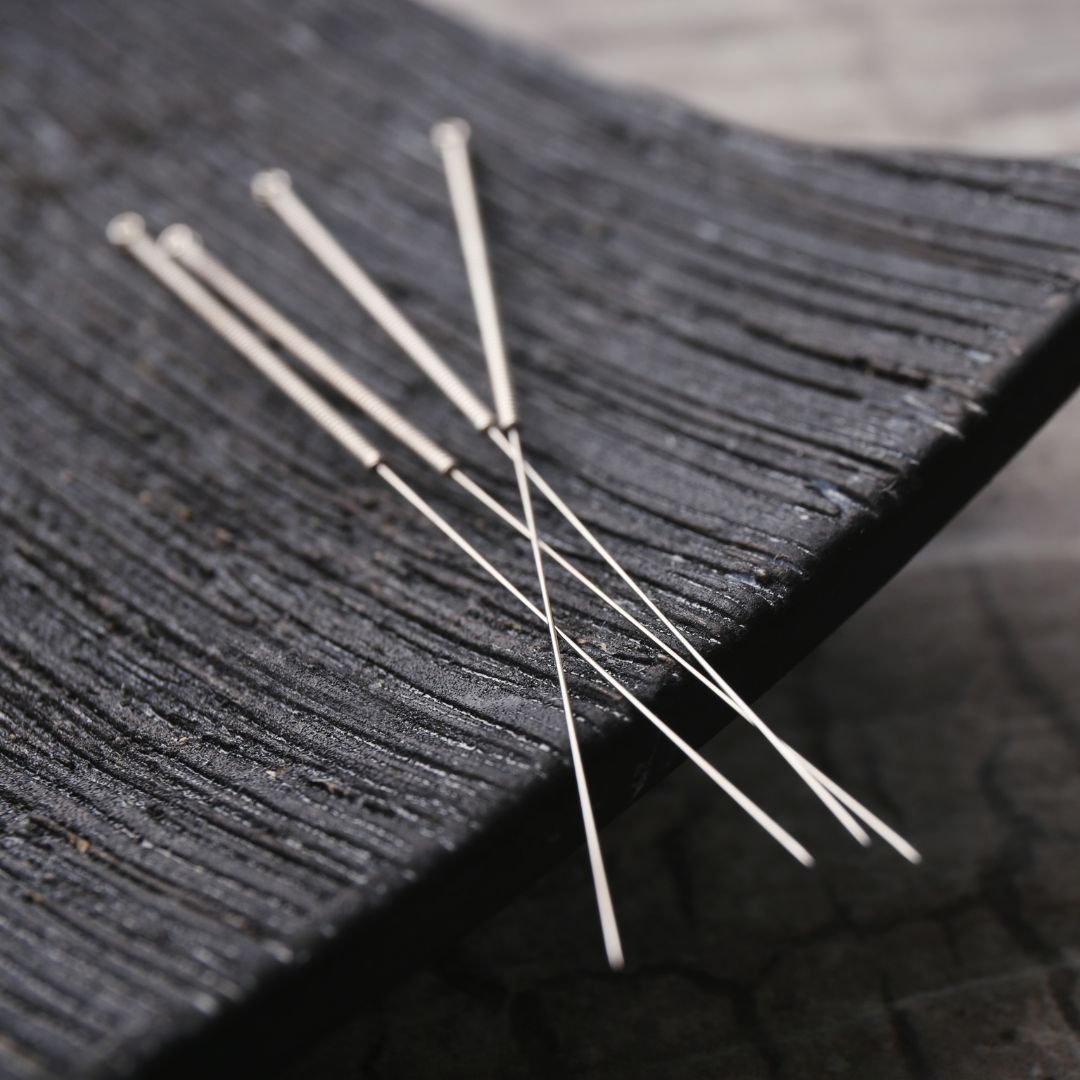 Acupuncture needles on a black surface. 
